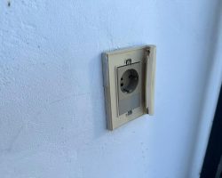 Steckdose mit abgebrochenem Wasserschutz im Außenbereich